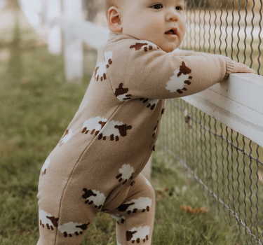 baby wearing organic cotton beige romper with sheep jacquard pattern and magnetic buttons from neck to crotch