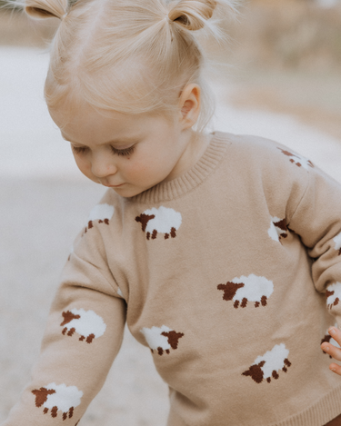 little girl wearing organic cotton beige sweater with sheep jacquard pattern