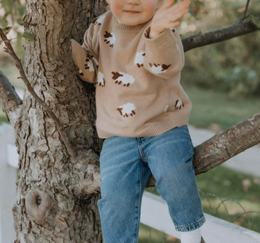 little girl wearing organic cotton beige sweater with sheep jacquard pattern