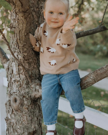 little girl wearing organic cotton beige sweater with sheep jacquard pattern