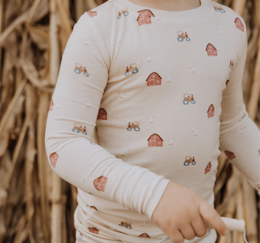 child wearing modal pajama set in light beige color with farm print