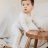 photo shows baby boy leaning on stool wearing modal footy pajamas in Paris print