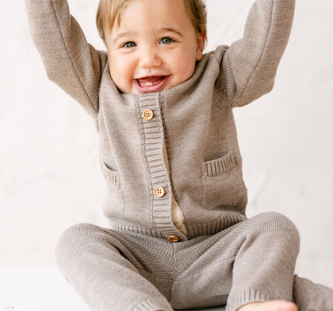 Image shows baby boy wearing merino wool baby gift set in heather brown. 