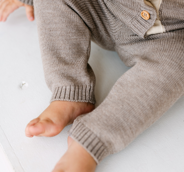 Image shows baby boy wearing merino wool baby gift set in heather brown. 