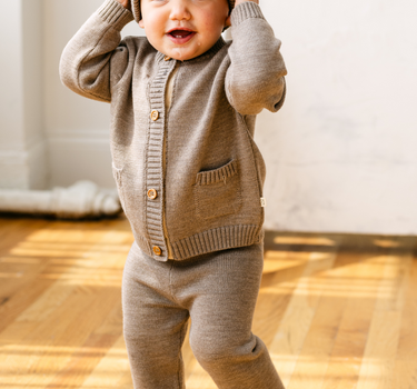 Image shows baby boy wearing merino wool baby gift set in heather brown. 