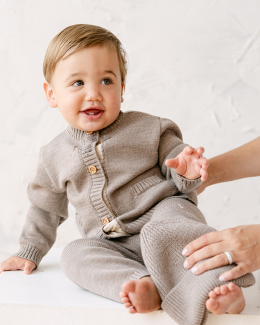 image shows baby boy wearing merino wool baby cardigan in heather brown