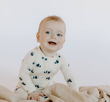 Image shows baby boy wearing modal convertible footy pajamas in panda print.