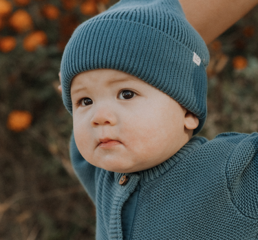 baby boy wearing organic cotton knit beanie in bluestone color