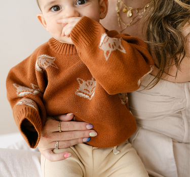 Image shows baby boy wearing organic cotton knit sweater with fox jacquard pattern in mocha. 