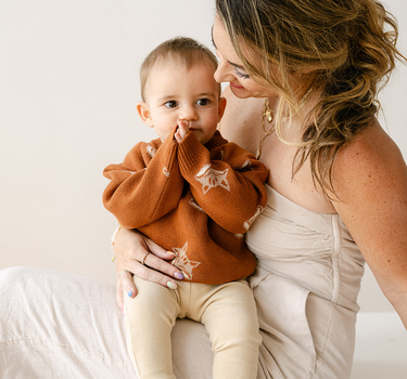 Image shows baby boy wearing organic cotton knit sweater with fox jacquard pattern in mocha. 