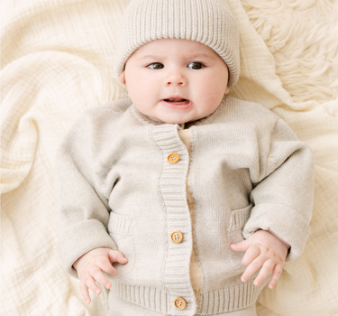 Image shows baby girl wearing merino wool baby gift set in light heather gray. 