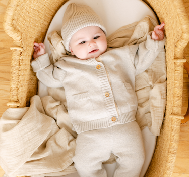 Image shows baby girl wearing merino wool baby cardigan in light heather gray. 