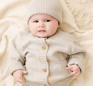 image shows baby girl wearing merino wool baby cardigan in light heather gray