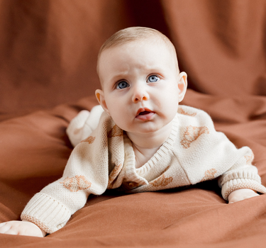 Image shows baby girl wearing organic cotton knit croissant romper.