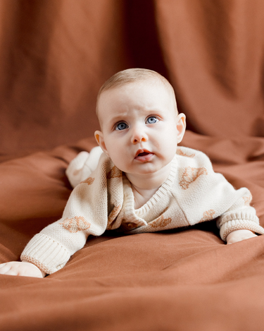 Image shows baby girl wearing organic cotton knit croissant romper.