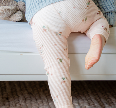 Image shows baby girl wearing organic cotton waffle leggings in bird print. 