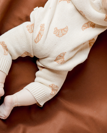 Baby laying on belly wearing organic cotton knit romper with croissant jacquard and Magnetic Buttons from neck to crotch.