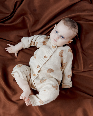 Baby laying on back wearing organic cotton knit romper with croissant jacquard pattern with Magnetic Buttons from neck to crotch. 