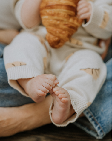 Baby wearing organic cotton knit croissant patterned joggers.