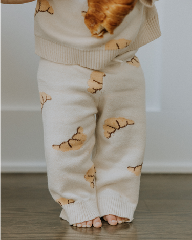 Baby wearing organic cotton knit croissant patterned joggers.