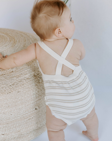Image shows back of baby girl wearing organic cotton knit stripe romper in mushroom beige.