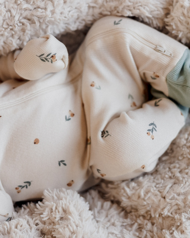 close up of body and feet of baby girl wearing organic cotton modal rib floral bud footy pajamas