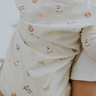 Baby wearing modal pajama set in Petit Déjeuner print with coffee mugs, croissants, butter, and jam.