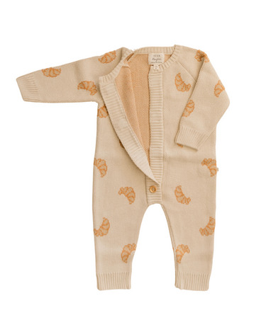 Flat lay photo of organic cotton knit romper with croissant pattern and magnetic buttons from neck to crotch.