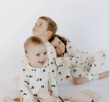 Image shows baby boy wearing modal convertible footy pajamas and toddler boy and girl wearing toddler modal pajama sets in panda print.