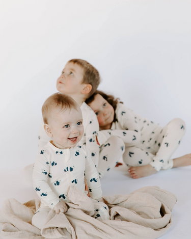 Image shows baby boy wearing modal convertible footy pajamas and toddler boy and girl wearing toddler modal pajama sets in panda print.