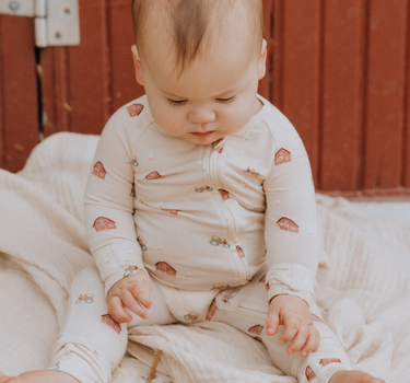 picture of baby boy wearing modal convertible footy pajamas in light beige color with farm print