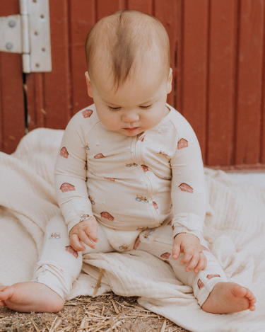 picture of baby boy wearing modal convertible footy pajamas in light beige color with farm print