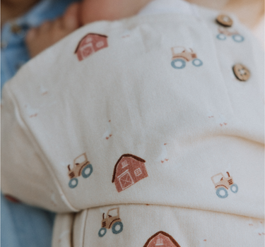 baby wearing organic cotton fleece sweatshirt in beige color with farm print and magnetic closures at the back of the neck