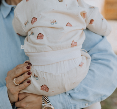 baby wearing organic cotton fleece sweatshirt in beige color with farm print and magnetic closures at the back of the neck