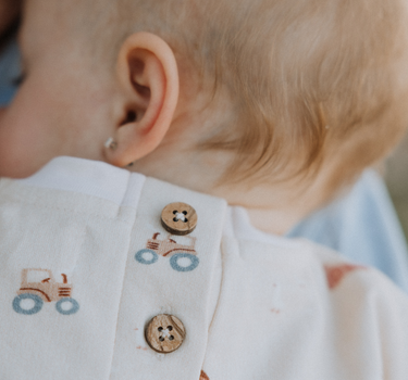 baby wearing organic cotton fleece sweatshirt in beige color with farm print and magnetic closures at the back of the neck