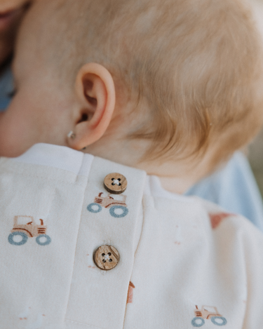 baby wearing organic cotton fleece sweatshirt in beige color with farm print and magnetic closures at the back of the neck