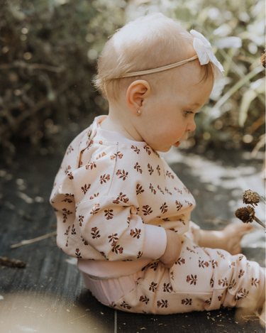 image of baby girl wearing organic cotton pink floral rose sweatshirt with magnetic buttons at the back of the neck