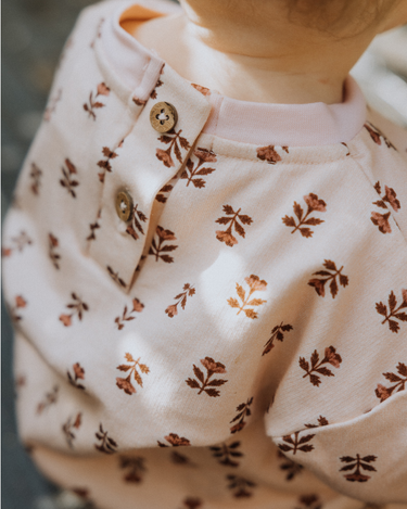 image of baby girl wearing organic cotton pink floral rose sweatshirt with magnetic buttons at the back of the neck