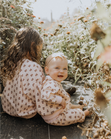 image of baby girl wearing organic cotton pink floral rose sweatshirt with magnetic buttons at the back of the neck