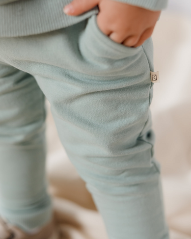 Image shows little boy wearing Organic Cotton Italian fleece joggers in jade color with his hand in one of the pockets.