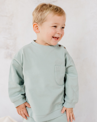 Image shows little boy standing and smiling wearing Organic Cotton Italian fleece sweatshirt in jade.
