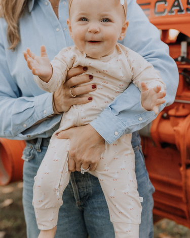 Baby wearing an organic cotton modal playsuit in geese pattern.