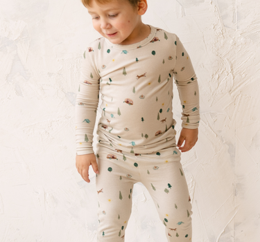 Image shows toddler boy wearing modal pajama set in camping print. 