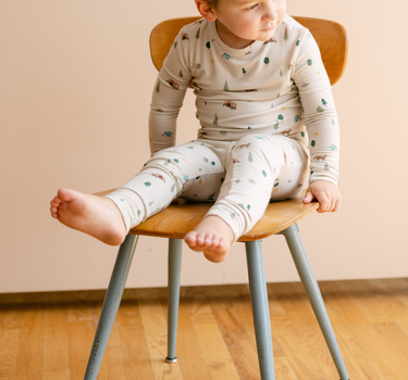 Image shows toddler boy wearing modal pajama set in camping print. 