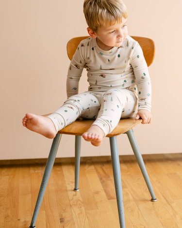 Image shows toddler boy wearing modal pajama set in camping print. 