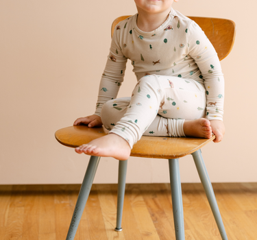 Image shows toddler boy wearing modal pajama set in camping print. 