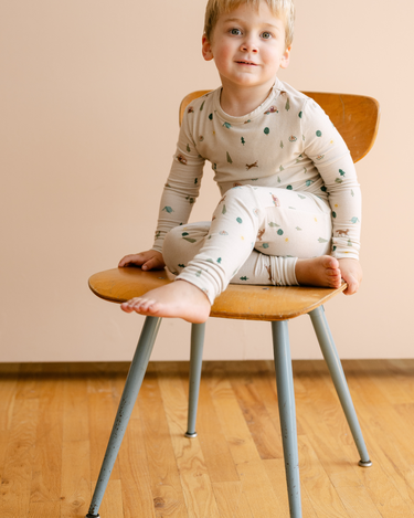 Image shows toddler boy wearing modal pajama set in camping print. 