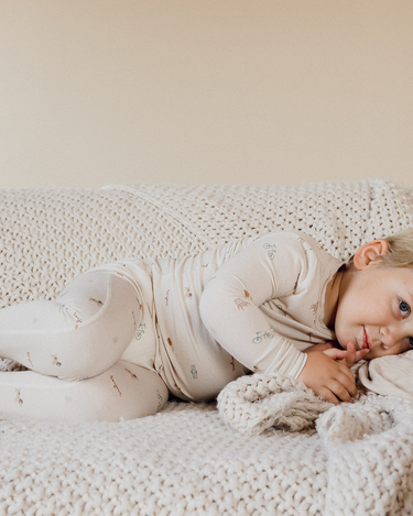 photo shows toddler boy laying on couch wearing modal pajama set in Paris print