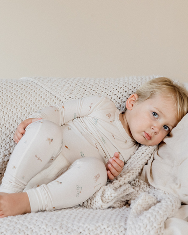 photo shows toddler boy resting on couch wearing modal pajama set in Paris print