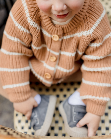 Picture shows little boy wearing organic cotton knit cardigan in acorn and cream stripes with Magnetic Buttons.